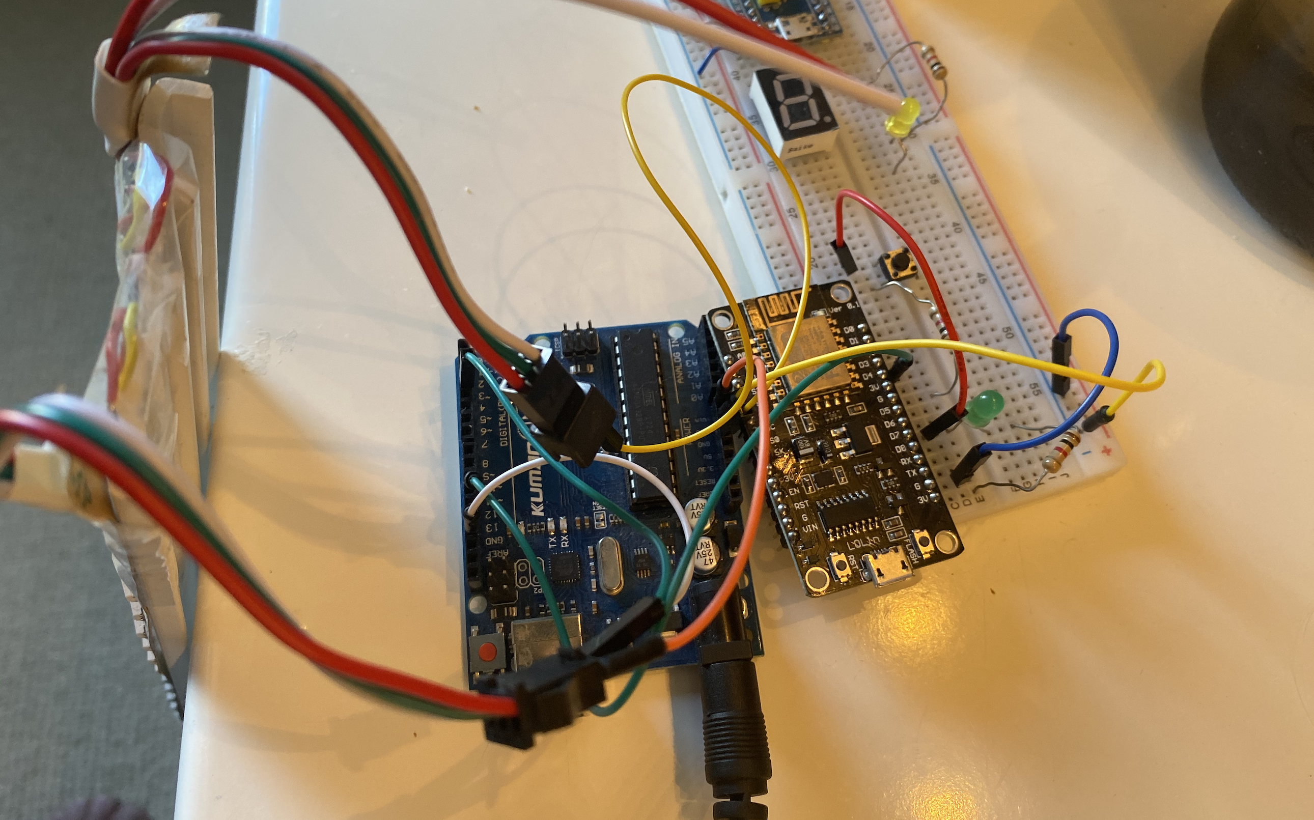 The ESP with a pushbutton input and serial output and the Arduino with a serial input and data/power/ground outputs to the LED strips. The LED strips are powered by the 12V DC source in the Arduino's barrel input.